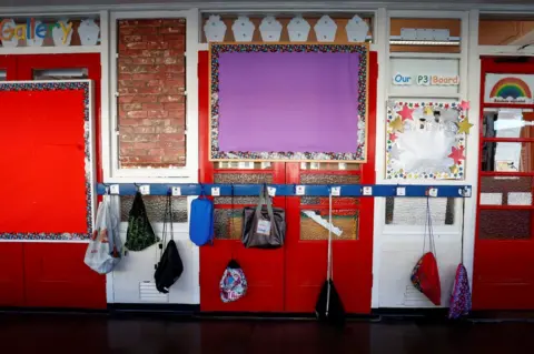 Reuters School bags hanging on hooks in a school corridor