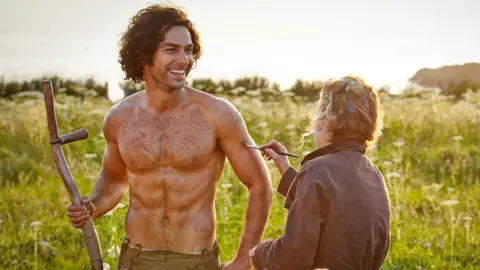 BBC Aidan Turner with make-up woman on the set of Poldark