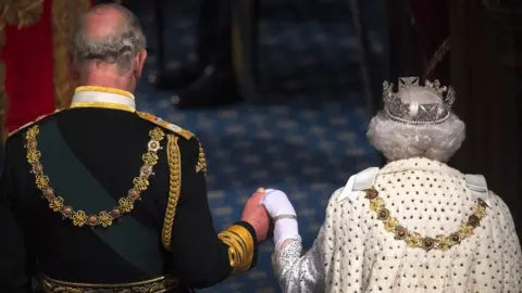 Getty Images The Queen and Prince Charles hold hands at the State Opening of Parliament in 2019