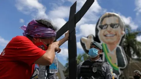 Reuters A protester holds a cross at a protest against Bolsonaro and his handling of the pandemic. File photo