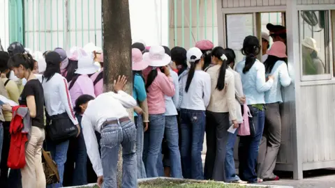 HOANG DINH NAM Women queue up outside the South Korean consulate for visa formalities in Ho Chi Minh city, on 15 March 2007