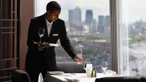 Getty Images A waiter lays out glasses on a table