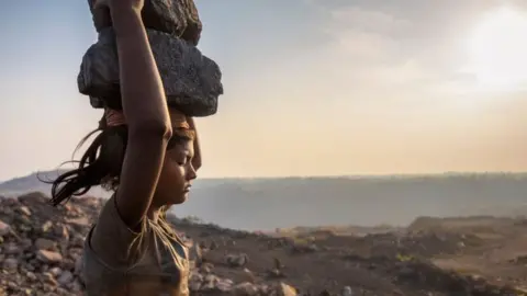 Getty Images A woman carries coal on her head while working in the Jharia coal field in Jharkhand