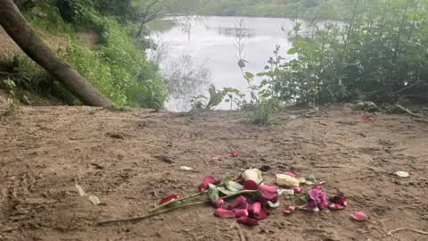 PA Flowers are at the scene of the riverbank where the boys got into difficulty. The petals are cream and purple.