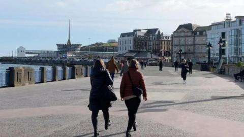 People walking along the prom in front of the sea terminal