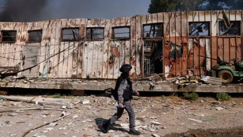 Getty Images A subordinate   of Israeli information    forces walks past   a damaged gathering  astatine  the tract  of a rocket onslaught   successful  Kiryat Shmona successful  bluish   Israel connected  24 September