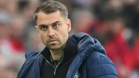 Getty Images Southampton manager Tonda Eckert is pictured looking in the general direction of the camera. He is wearing a black top with a zipped collar under a blue coat. The background is blurred and out of focus. 