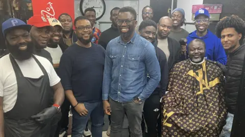 People attending the "Fade Therapy" sessions pose for a group picture. Two of the barbers are in the front row with the organisers of the project