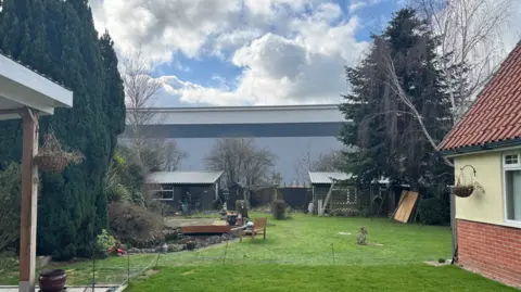 George King/BBC A ample  warehouse tin  beryllium  seen astatine  the extremity  of a large  backmost  garden, which has a tiny  pond and aggregate  sheds. 