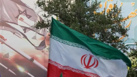 Reuters FILE PHOTO: An anti-Israel billboard is seen next to the Iranian flag during a celebration following the IRGC attack on Israel, in Tehran, Iran, April 15, 2024.