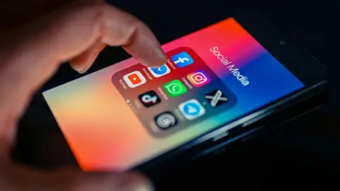 Getty Images A stock image showing a man's forefinger reaching for the Facebook Messenger app icon on a smartphone.
