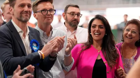 PA Media Natasha Asghar is stood with three men to the left of her and an older woman to her right.