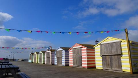 Blue sky above a row of beach huts along the coast at Hastings. 