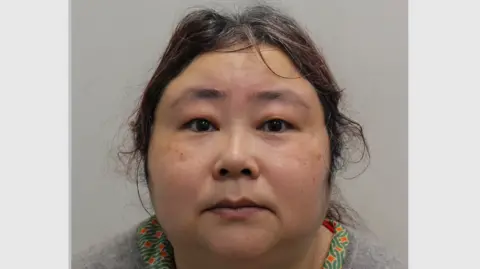 Metropolitan Police A mugshot of Zhimin Qian, pictured staring into the camera. She has curly hair and is dressed in a grey jumper.