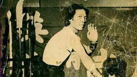 Liverpool Hung Gar Kung Fu Club A black and white image of Master Jimmy Chan on the front cover of Karate and Oriental Arts Magazine. He is performing a martial arts pose in his club with a traditional Chinese lion dance costume to the right. 