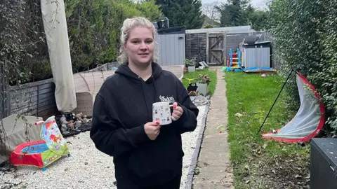 Catherine Urben stood in her back garden, with children's toys in the background