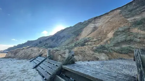 North Norfolk District Council Parts of a cliff are now on the sand after falling. There are wooden structures on the beach