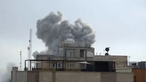 A plume of smoke rises above a building in Tehran, Iran.