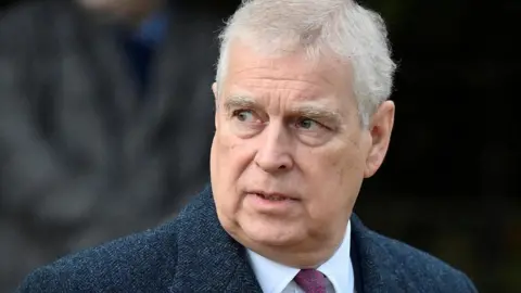 Reuters Headshot of Andrew who looks off to the side with his mouth slightly open. The background is blurry but it appears there's a person walking behind him. Taken in December 2022