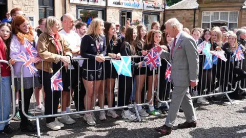 PA Media A big gathering of people waving flags to greet King Charles