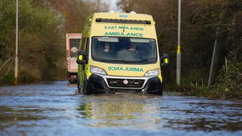 An ambulance drives through floodwater in Northamptonshire