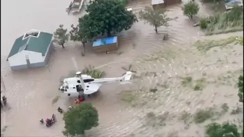 Aerial shot of a helicopter rescuing survivors in a flooded area