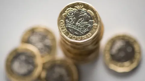 PA Media A stack on £1 coins on a white table.