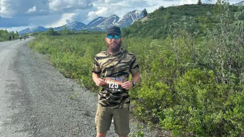 Andrew Kelly Kelly poses with his race number against Alaska's snow-capped mountains during the Denali 135, where he finished second