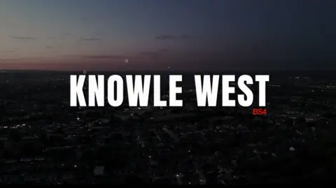 Neil Maggs Knowle West at night time, with fading sunlight on the horizon. The city is lit with street lights. The text "Knowle West" in white capitals is imposed over the image, along with the text "BS4" in red. 