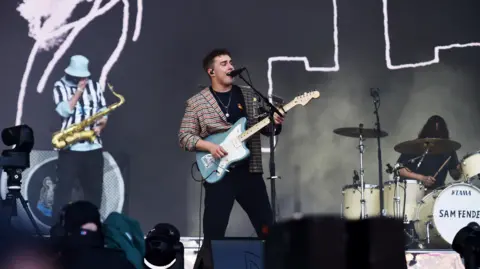 Sam Fender holds a blue electric guitar and performs at Glastonbury 2022