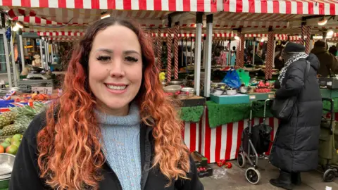 A woman stood in front of a stall selling a range of fruits