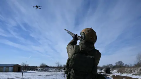 A Russian soldier, in uniform, aims at a drone while undergoing an intensive combat training course