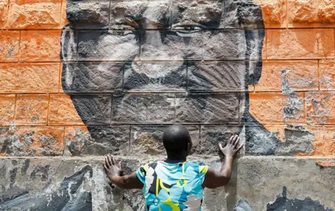 MONICAH MWANGI / REUTERS A woman places her hands on a mural depicting Raila Odinga and wails.
