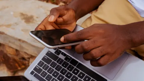Getty Images Stock photo of a student with laptop and phone in Tema, Ghana