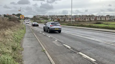 Leanne Rinne/BBC A line of cars driving along the A259 road in Newhaven in the direction of Seaford on a grey cloudy day. 