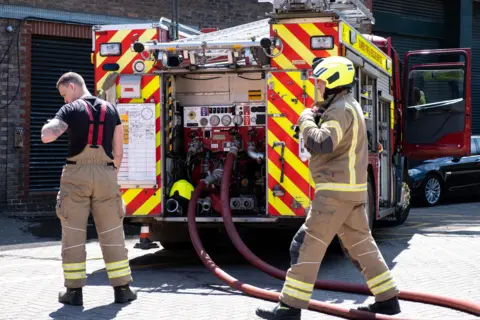 Fire engine and fire fighters attending a fire in a public car park.