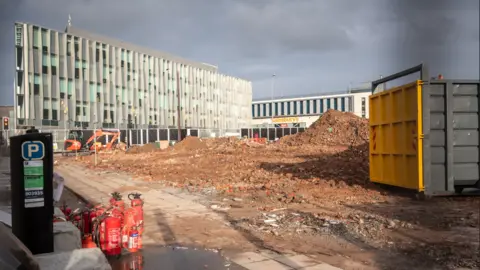 LDRS Mound of rubble stand where building work has taken place with a Sainsbury's supermarket in the background