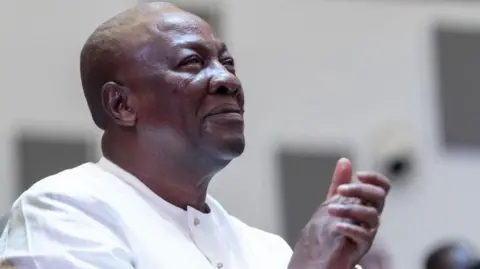 Getty Images Ghana's former president John Mahama wearing a white linen shirt and clasping his hands.