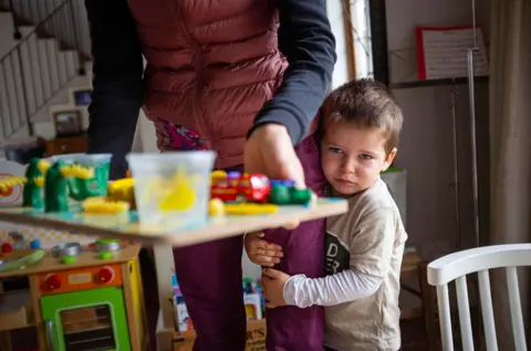 Karel Prinsloo / Unicef An upset child clings to its parents legs