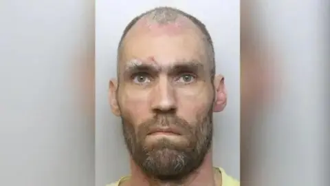 Mugshot of convicted sex offender Robert Emmerson. He has short, receding and greying hair and a beard.