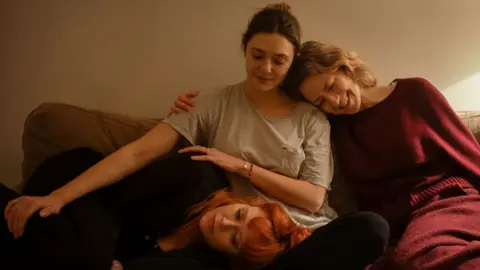 Netflix Actresses Elisabeth Olsen (centre), Carrie Coon (right) and Natasha Lyonne seen in His Three Daughters sitting together on a sofa