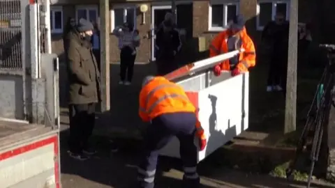 Two people in high-vis jackets take away the freezer