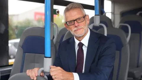 Stagecoach A man with white stubble and hair is smartly dressed and sat in a bus