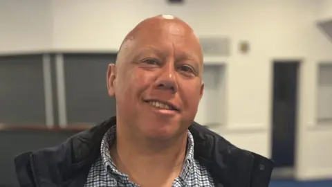BBC A picture of Deputy Ross Le Brun. He is wearing a checkered shirt and a black jacket.