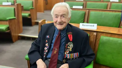 A decorated veteran sat on the green leather seats of the council chamber