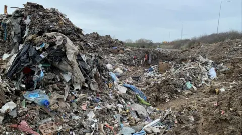Environment Agency Piles of rubbish can be seen at a muddy site