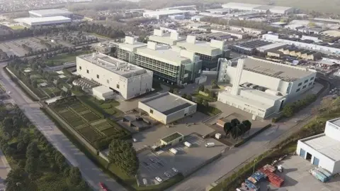 An artist's impression of the aerial view of how the project would look. It is a large site with several big, white industrial buildings. It is based on a sprawling industrial estate and has trees and grass on one side.