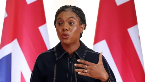 EPA Kemi Badenoch giving a speech in front of two Union Jacks.