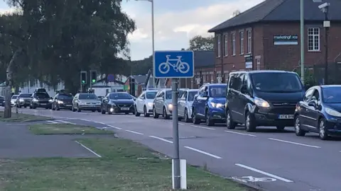 Vikki Irwin/BBC A general view of a road in Suffolk that is congested. Cars can be seen queuing up one behind each other on one side of the road. The opposite side of the road is car free