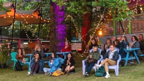 Edinburgh International Book Festival People attending a Book Festival online screening relax in the grounds of the Edinburgh College of Art